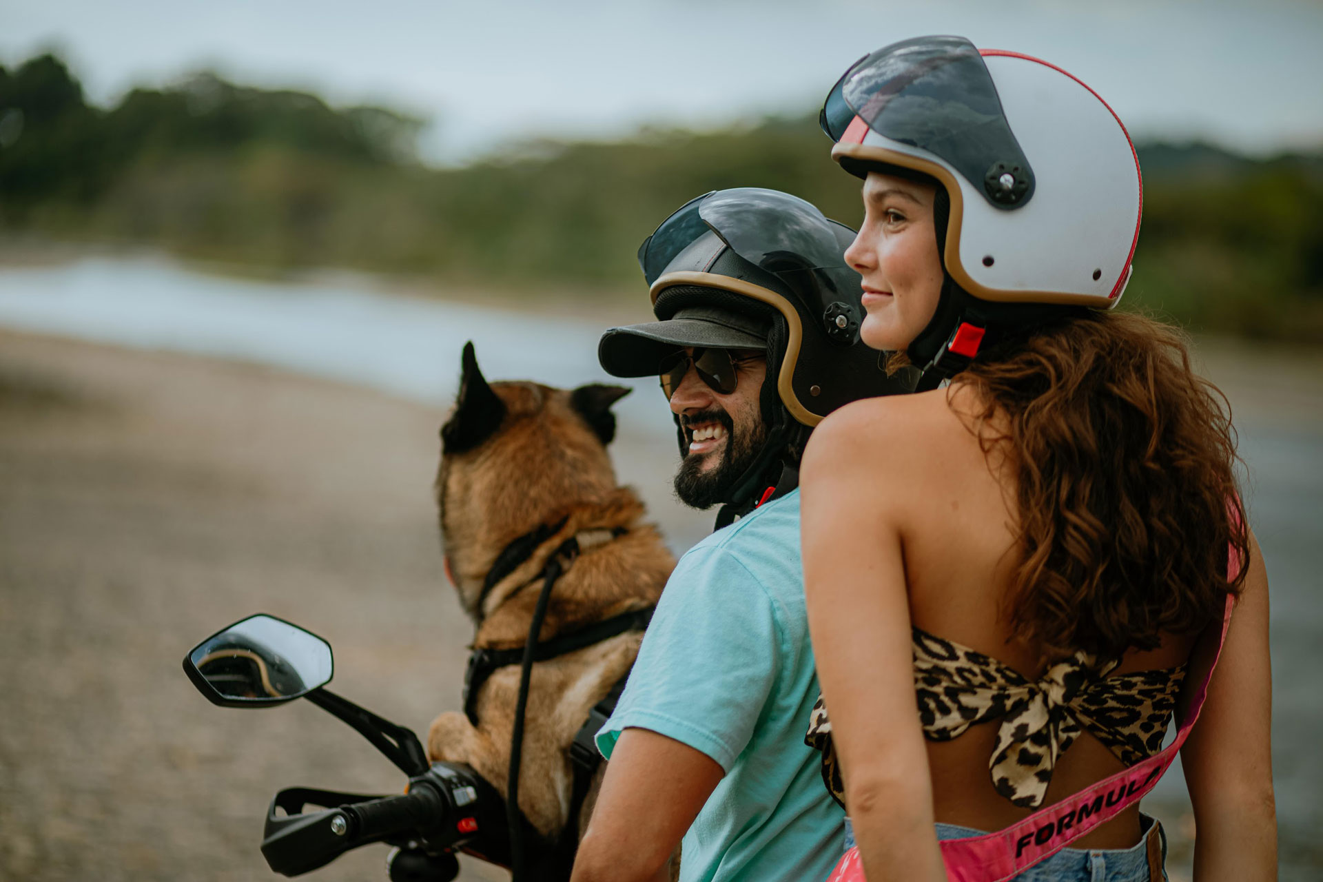 Couple riding rented scooter with their dog